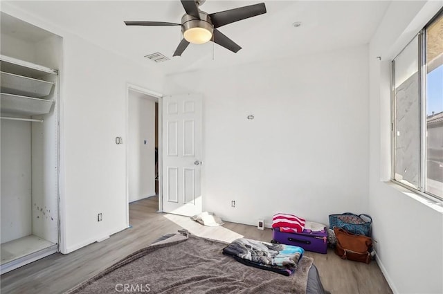 bedroom with ceiling fan, light hardwood / wood-style floors, and a closet