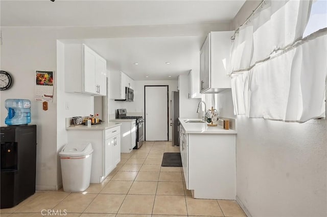 kitchen featuring sink, stainless steel appliances, white cabinetry, and light tile patterned flooring