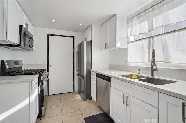 kitchen with appliances with stainless steel finishes, white cabinetry, light tile patterned flooring, and sink