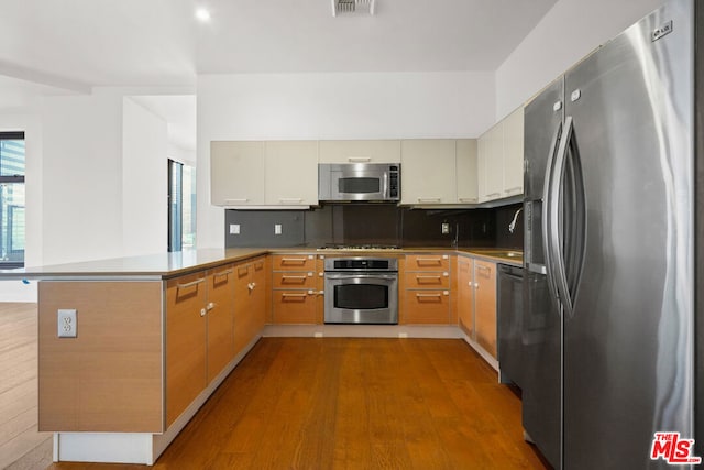 kitchen with a wealth of natural light, stainless steel appliances, kitchen peninsula, and tasteful backsplash