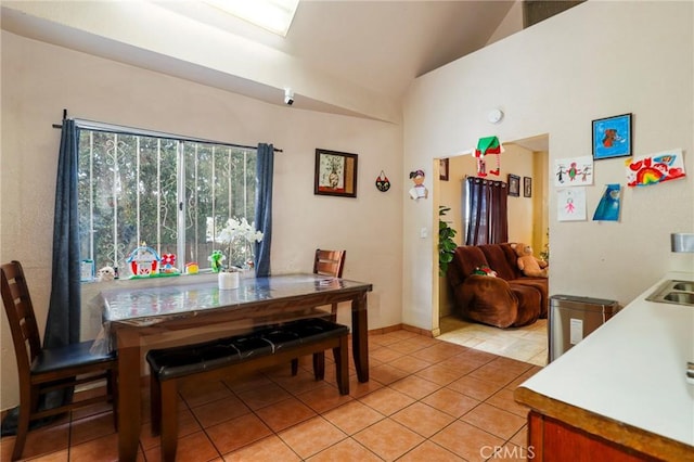 tiled dining room with sink and lofted ceiling