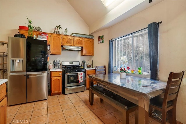 kitchen with vaulted ceiling, appliances with stainless steel finishes, and light tile patterned flooring