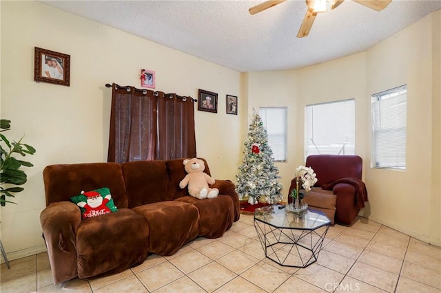 living room featuring ceiling fan, light tile patterned floors, and a textured ceiling