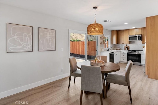 dining space with sink and light wood-type flooring