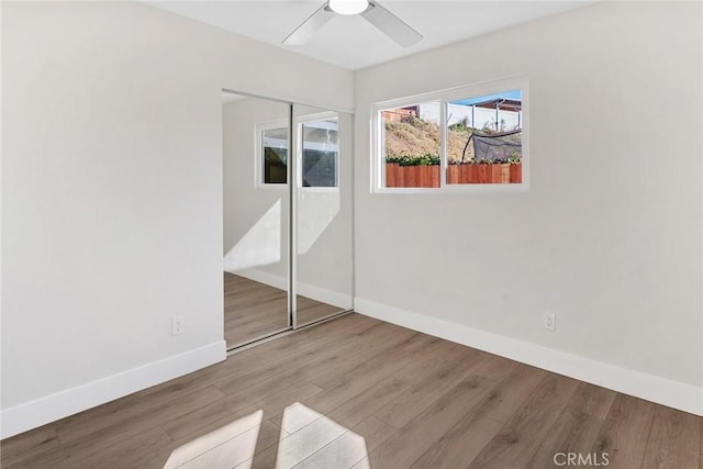 unfurnished bedroom featuring ceiling fan, wood-type flooring, and a closet