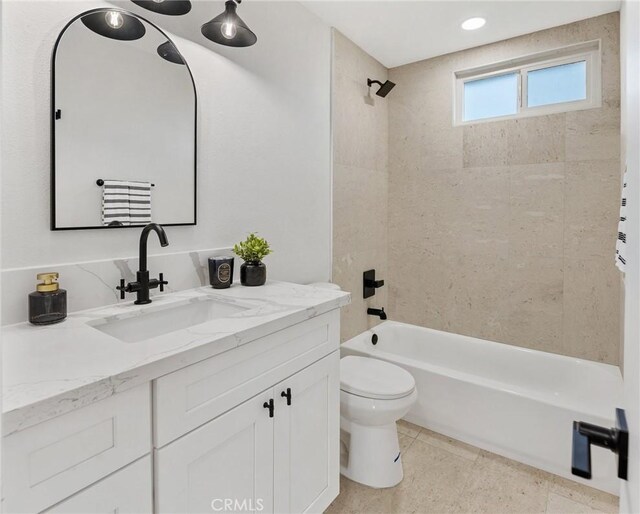 full bathroom featuring toilet, tiled shower / bath, and vanity