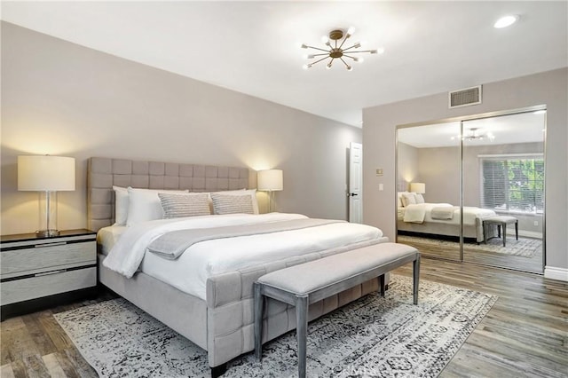 bedroom with a closet, hardwood / wood-style floors, and a notable chandelier