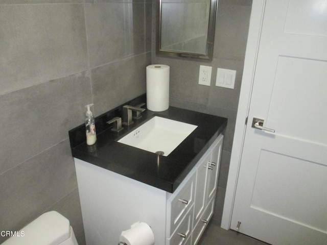 bathroom with toilet, decorative backsplash, tile walls, and vanity