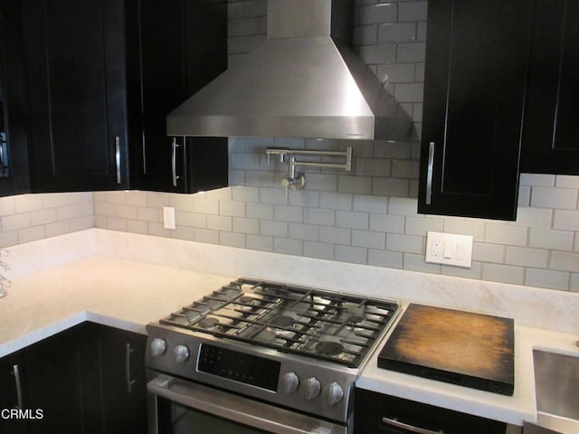 kitchen featuring backsplash, wall chimney range hood, and stainless steel stove