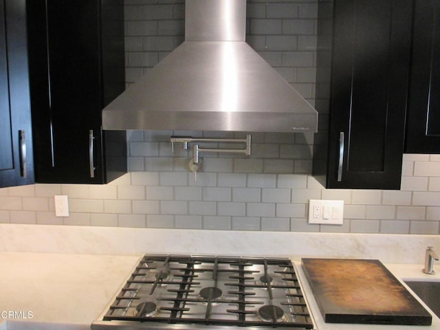 kitchen with stainless steel gas stovetop, wall chimney range hood, and tasteful backsplash