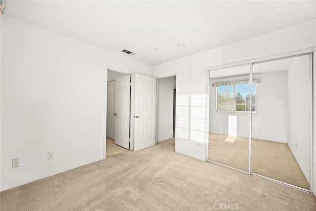 unfurnished bedroom with light colored carpet and a closet