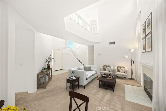 carpeted living room with a high ceiling and a tiled fireplace