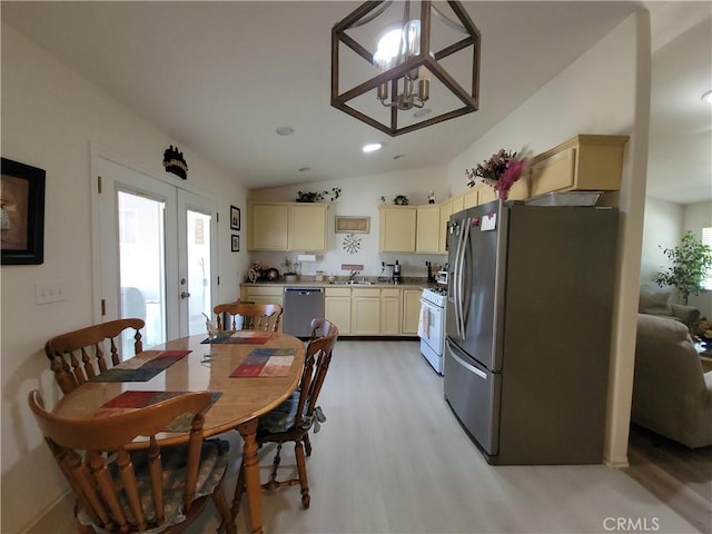 dining room with lofted ceiling, french doors, light hardwood / wood-style floors, sink, and a chandelier