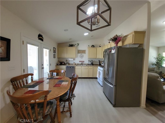 dining space with an inviting chandelier, french doors, vaulted ceiling, light hardwood / wood-style flooring, and sink