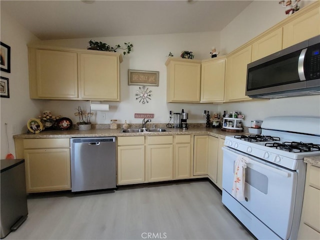 kitchen featuring stainless steel appliances, cream cabinets, light hardwood / wood-style flooring, and sink