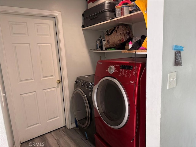 laundry room with washing machine and clothes dryer and hardwood / wood-style floors