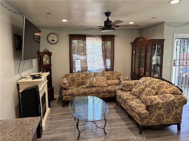 living room featuring ceiling fan, wood-type flooring, and a wealth of natural light