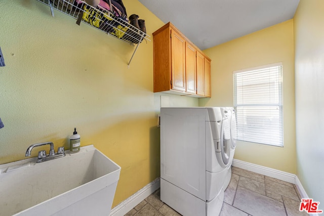 washroom featuring cabinets, sink, washer and clothes dryer, and a healthy amount of sunlight