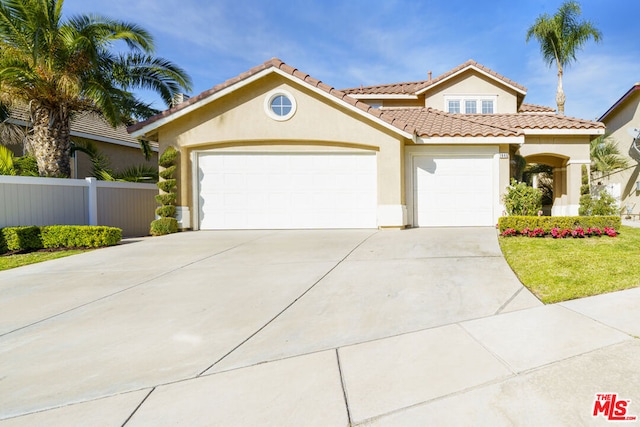 mediterranean / spanish-style home with a front yard and a garage