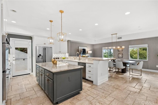 kitchen with sink, white cabinets, hanging light fixtures, and a center island