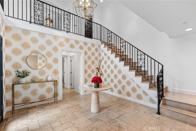 stairway with a chandelier and a towering ceiling