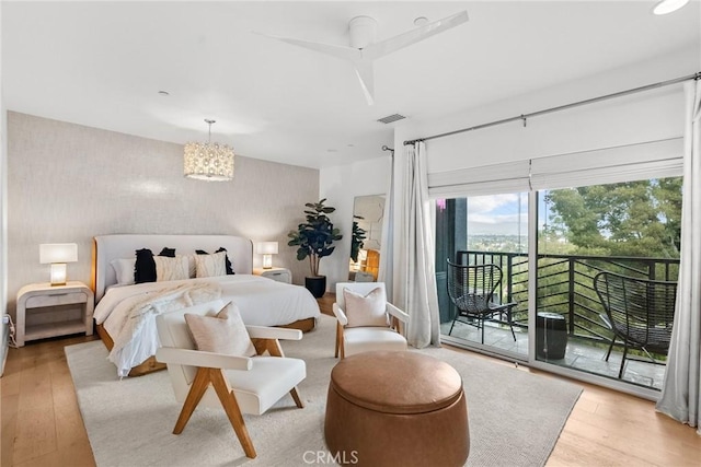 bedroom featuring light hardwood / wood-style floors, access to outside, and a notable chandelier