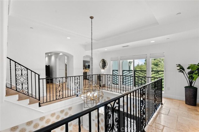 hall featuring a tray ceiling and a notable chandelier