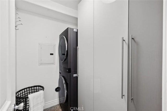 clothes washing area featuring stacked washer / drying machine and electric panel