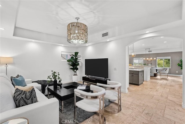 living room with an inviting chandelier and a tray ceiling