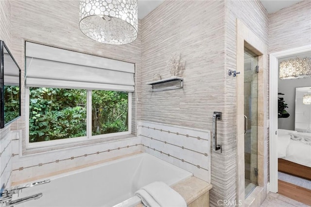 bathroom featuring a chandelier and plus walk in shower