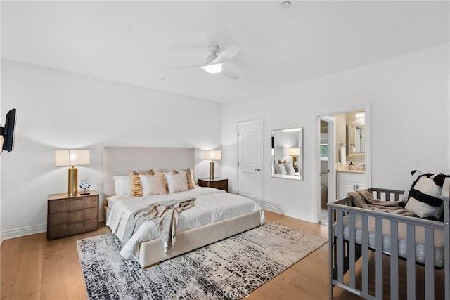 bedroom featuring ceiling fan, ensuite bath, and light wood-type flooring