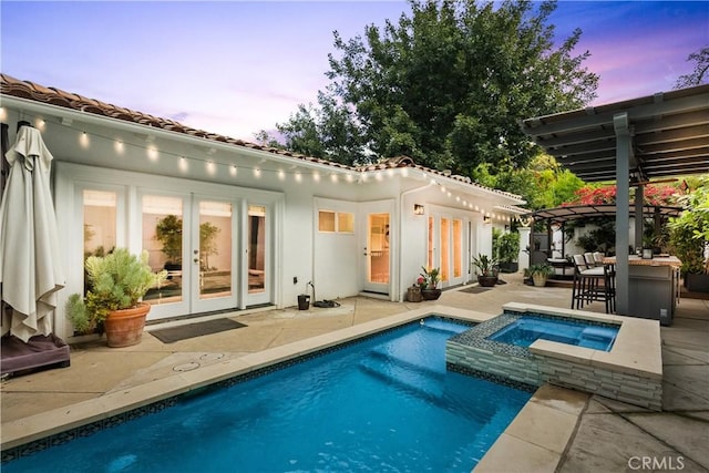 back house at dusk featuring a patio area, a pool with hot tub, french doors, and a pergola