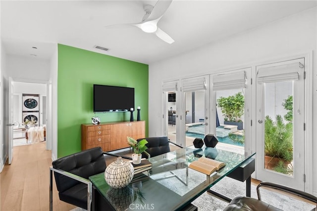 living room featuring ceiling fan, light hardwood / wood-style floors, french doors, and stacked washer and dryer