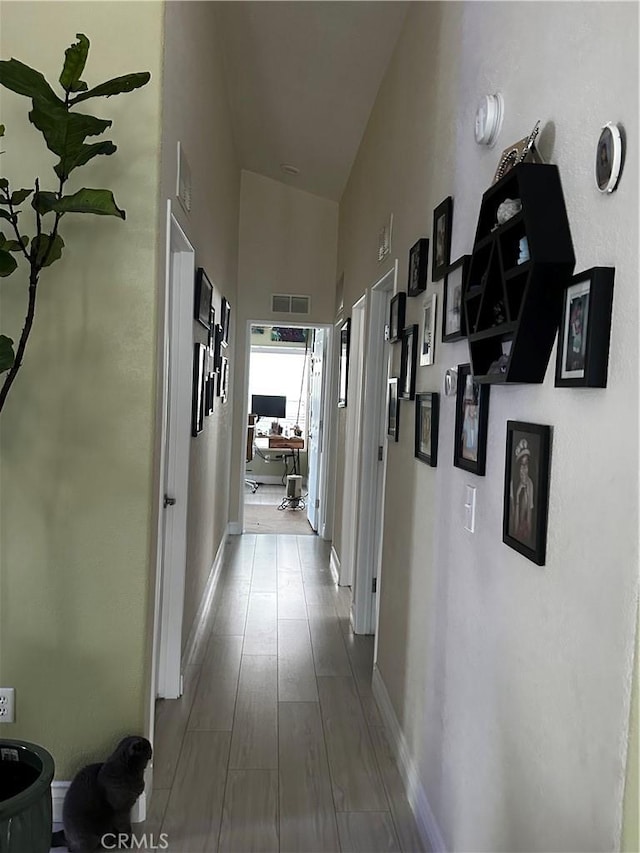 hallway featuring hardwood / wood-style flooring and high vaulted ceiling