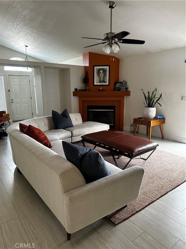 living room featuring ceiling fan, vaulted ceiling, a textured ceiling, and hardwood / wood-style flooring