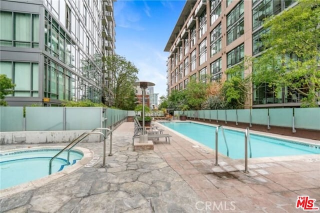 view of swimming pool featuring a hot tub and a patio