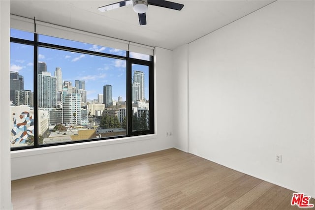 spare room with ceiling fan, a wealth of natural light, and hardwood / wood-style flooring