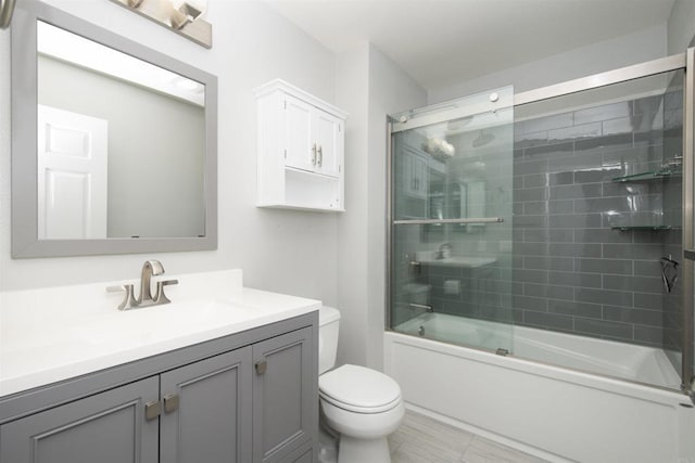 full bathroom featuring toilet, bath / shower combo with glass door, and vanity