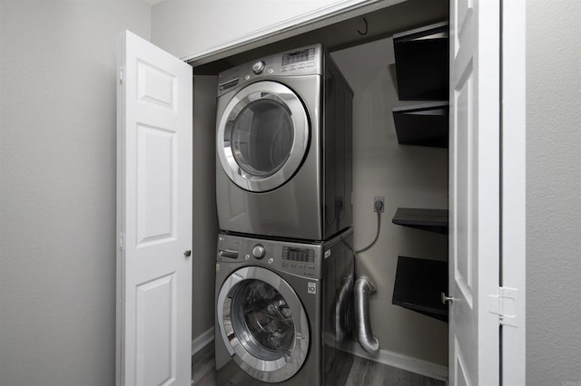 washroom with stacked washer / drying machine and wood-type flooring