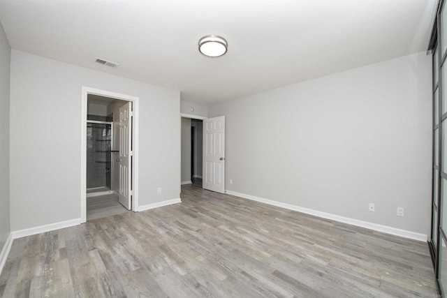 unfurnished bedroom featuring light hardwood / wood-style floors and ensuite bathroom