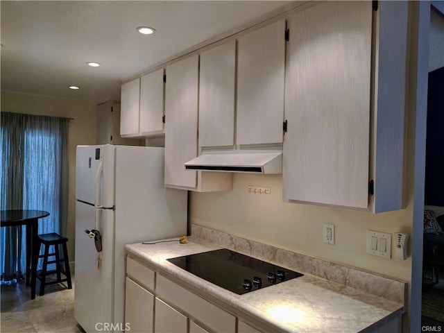 kitchen with black electric stovetop and white fridge