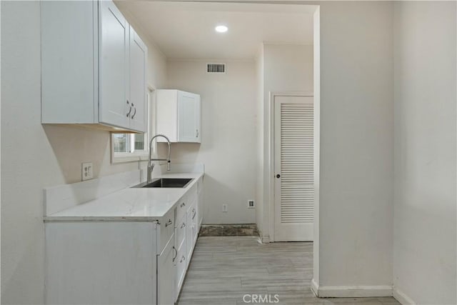 kitchen featuring white cabinets, light stone countertops, and sink