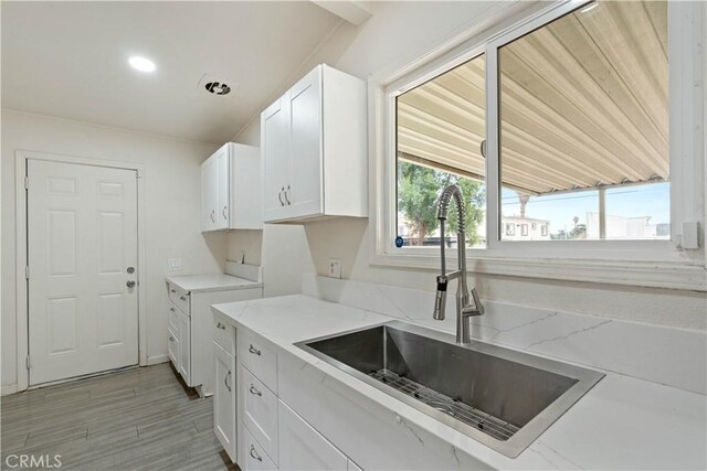 kitchen featuring white cabinets, light stone countertops, and sink