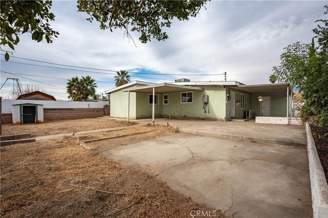 rear view of house with central AC, a carport, and a storage unit