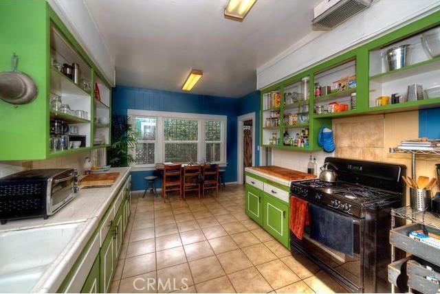 kitchen with gas stove, tile counters, light tile patterned floors, and sink