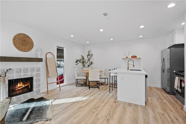 kitchen featuring light hardwood / wood-style floors, a center island with sink, a kitchen bar, appliances with stainless steel finishes, and sink