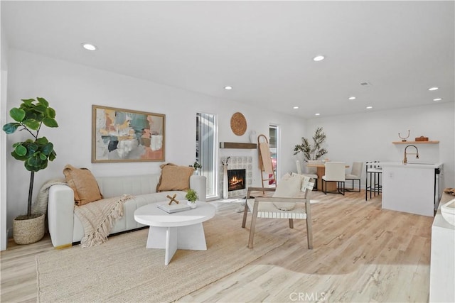 living room with sink, light hardwood / wood-style flooring, and a fireplace