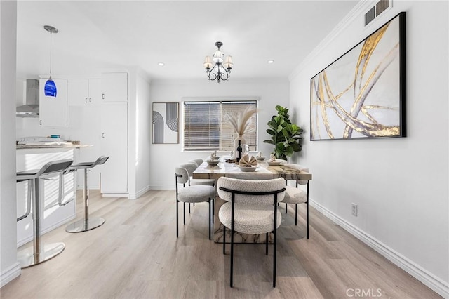 dining area featuring light hardwood / wood-style floors, ornamental molding, and a notable chandelier