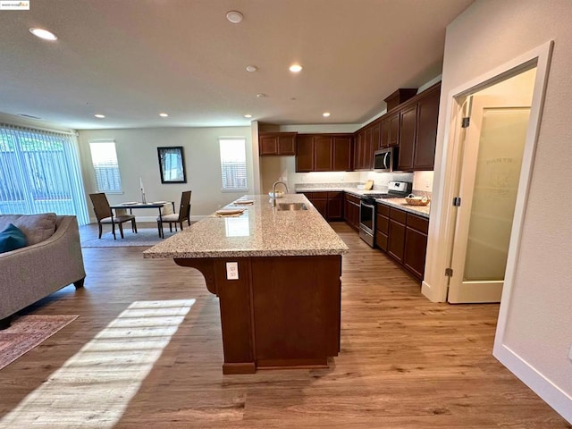 kitchen featuring appliances with stainless steel finishes, sink, a kitchen breakfast bar, a kitchen island with sink, and light hardwood / wood-style flooring