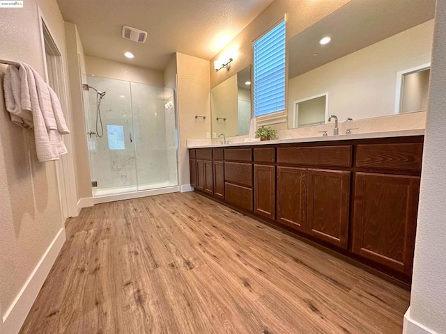 bathroom with a shower with door, hardwood / wood-style flooring, and vanity